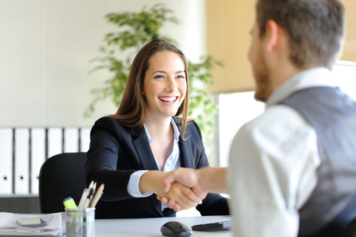 Smiling professionals shaking hands during a medical office specialist job interview