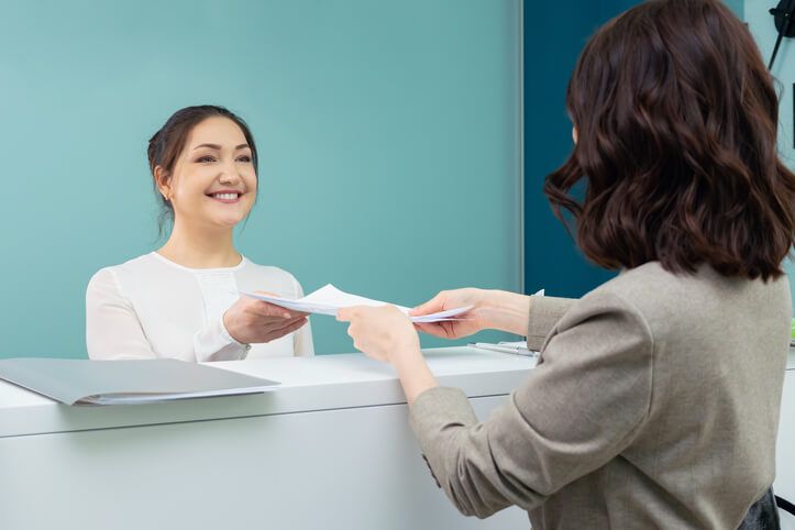 A woman holding a pen ready to write on a piece of paper after medical office specialist training