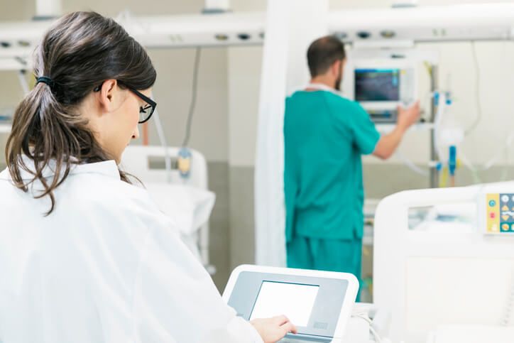 A male EKG technician working in the background after medical office specialist training