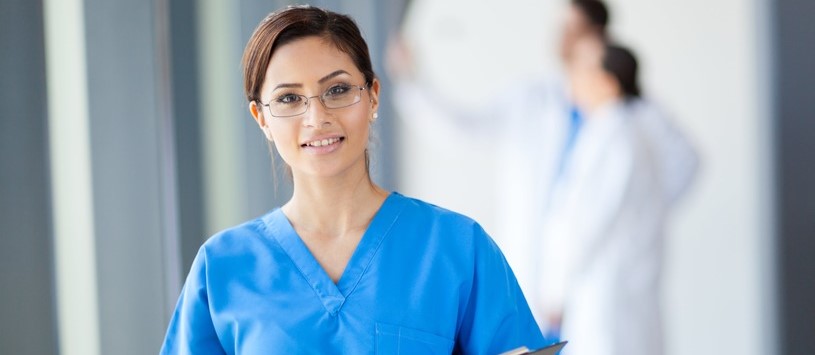 Medical Assistant holding a clipboard in a healthcare setting.