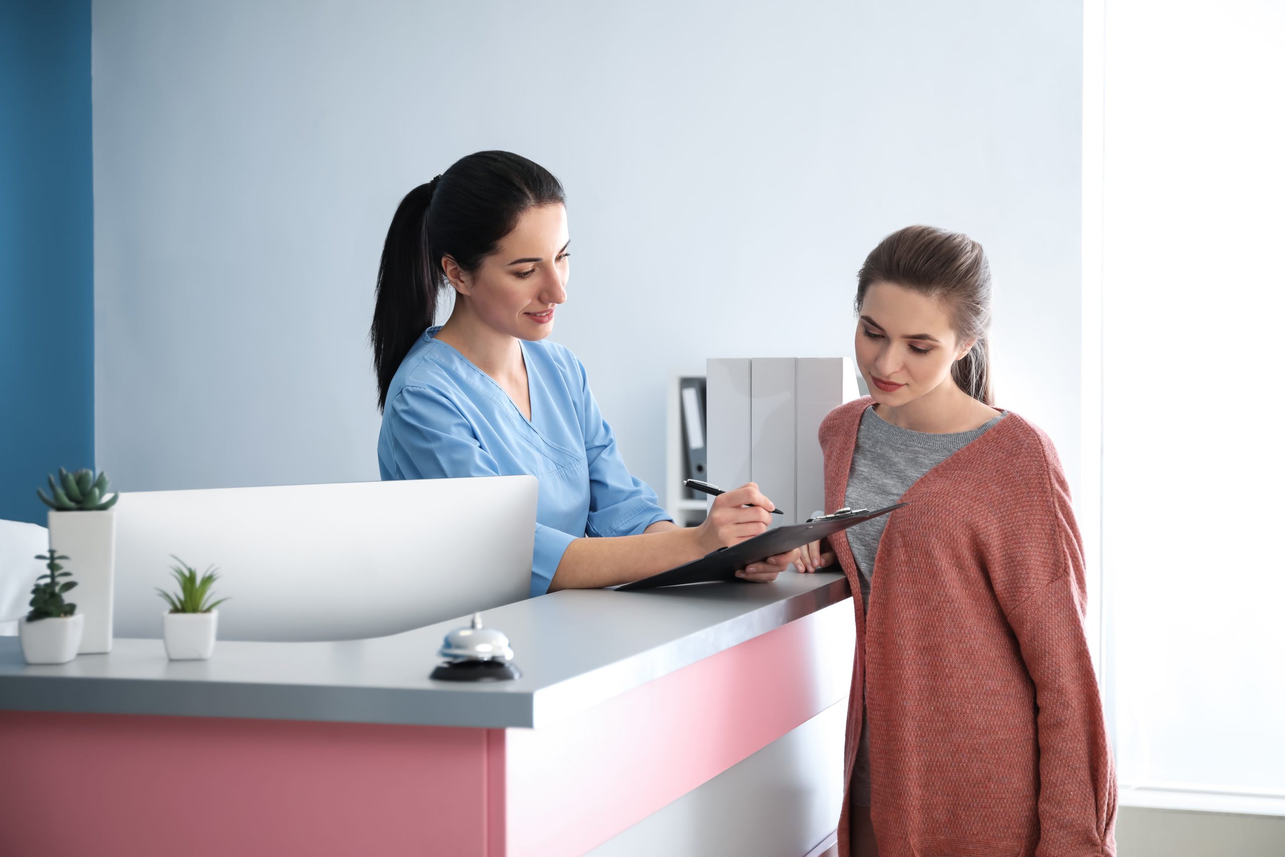 woman at a desk with a clipboard reviewing paperwork